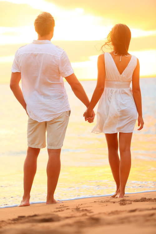 Young couple holding hands at beach sunset